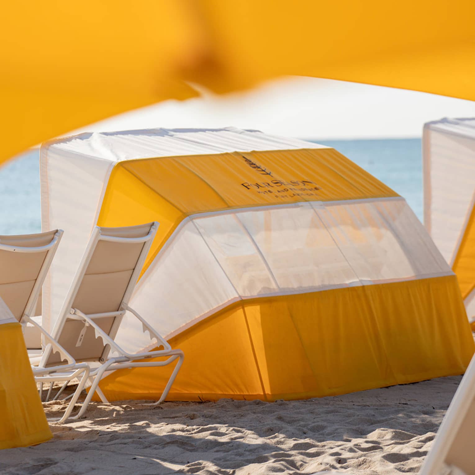 A daybed on the beach with lounge chairs