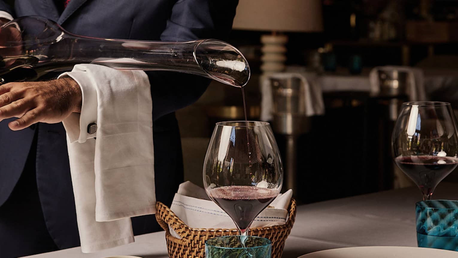 Red wine being poured into a glass from a long-necked decanter