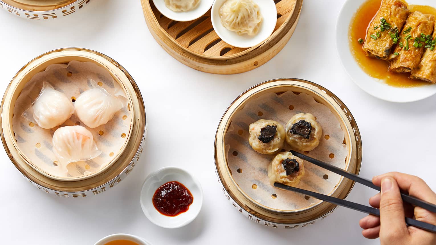 Aerial shot of Dim Sum selection, man reaching for dumplings steamer basket with chopsticks
