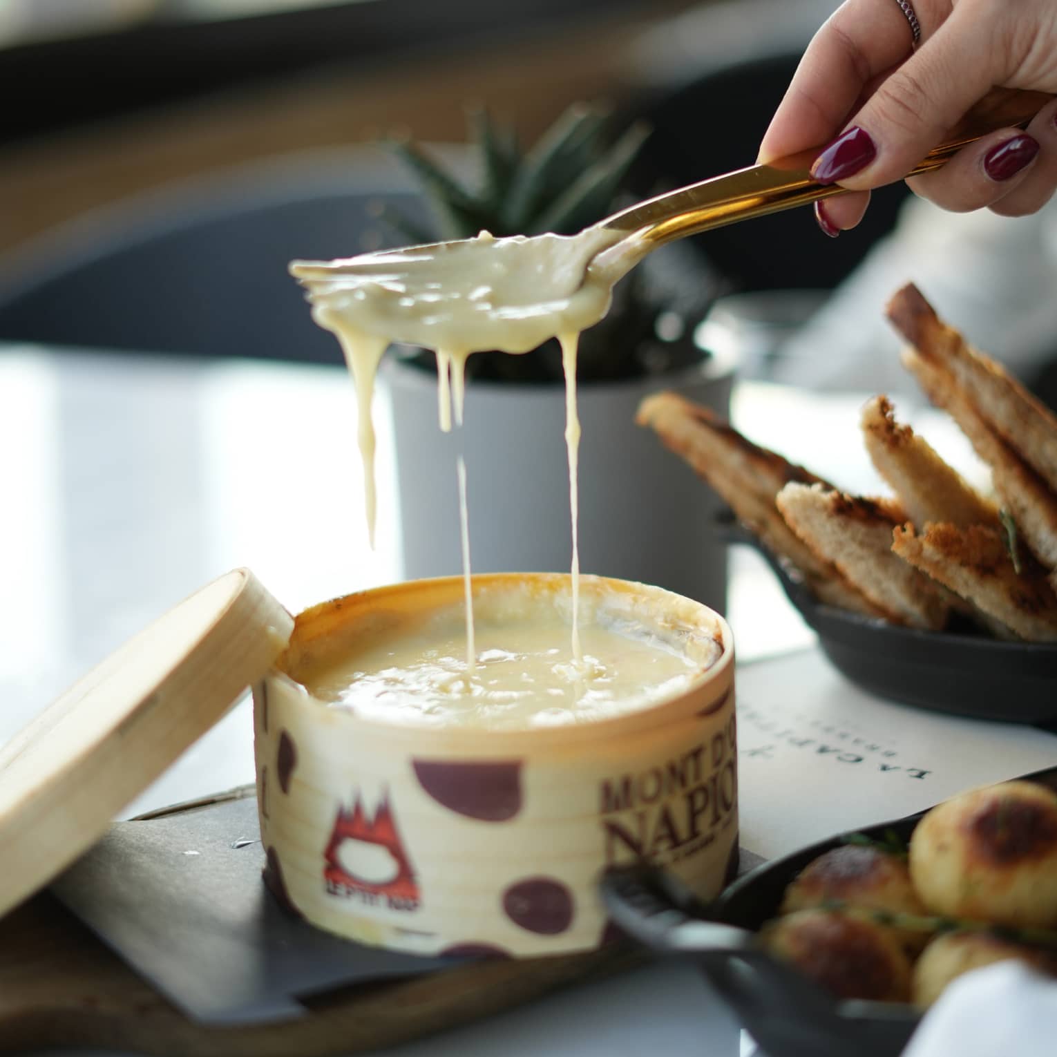 Hand holding a spoon and fork scoops out a serving of melted cheese