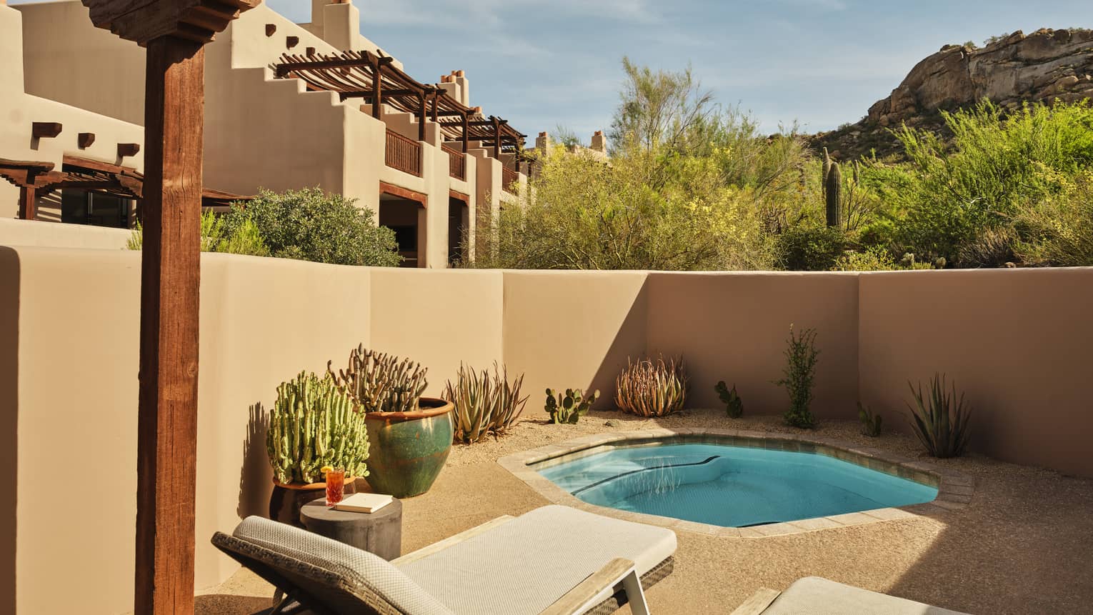 Plunge pool and two sun loungers on a walled-in terrace surrounded by desert landscape