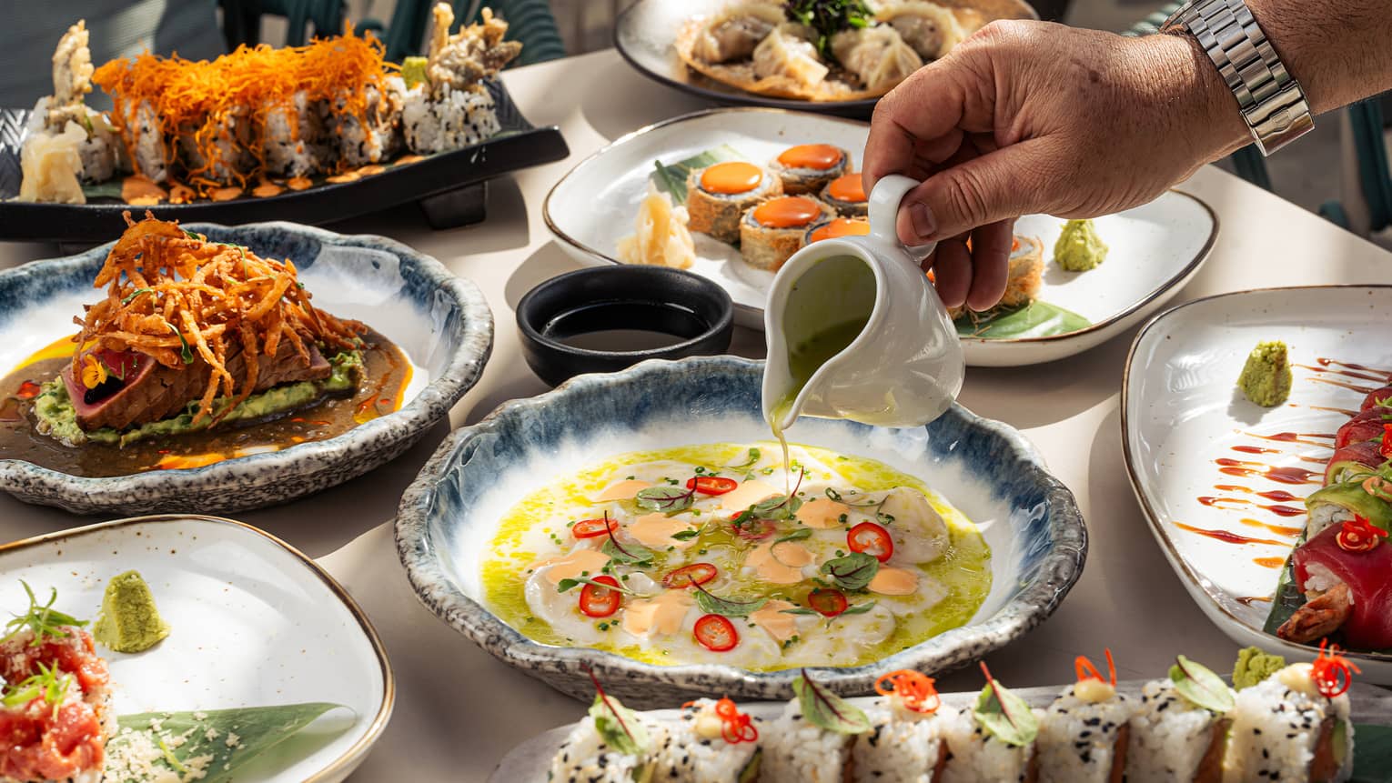 Outdoor table filled with an assortment of sushi and other Asian-inspired dishes