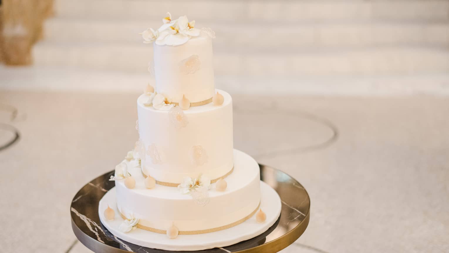 Three-tiered white wedding cake with fresh white orchid details