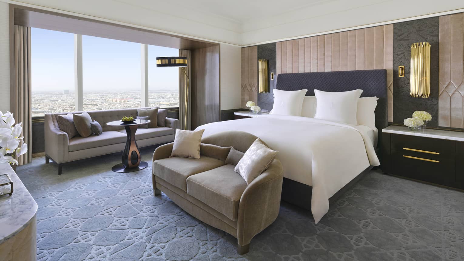 Bedroom with king bed, gold sconces, love seat and window-side chaise
