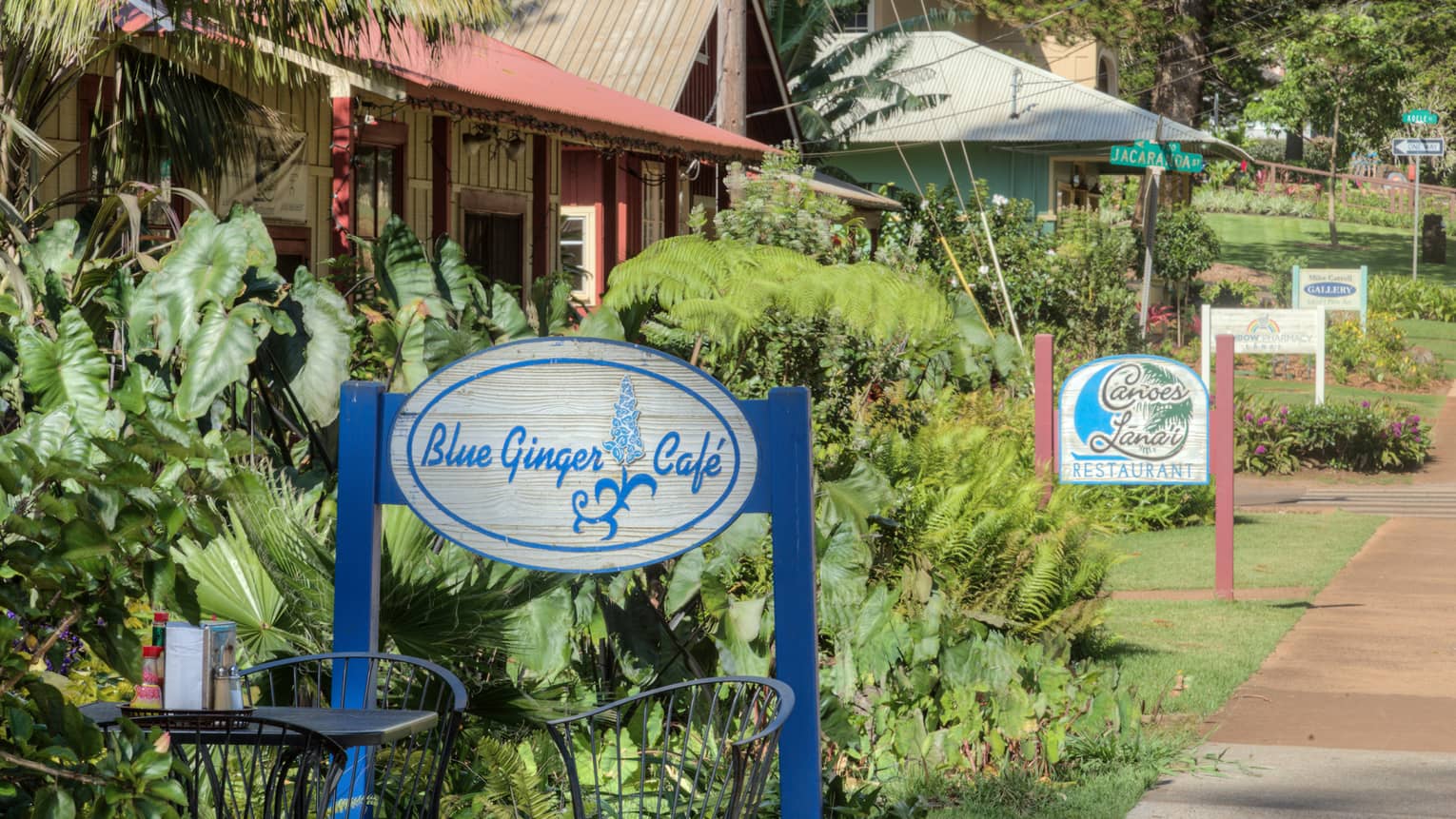 Garden patio table under Blue Ginger Cafe sign, path leading to more cafes and shops