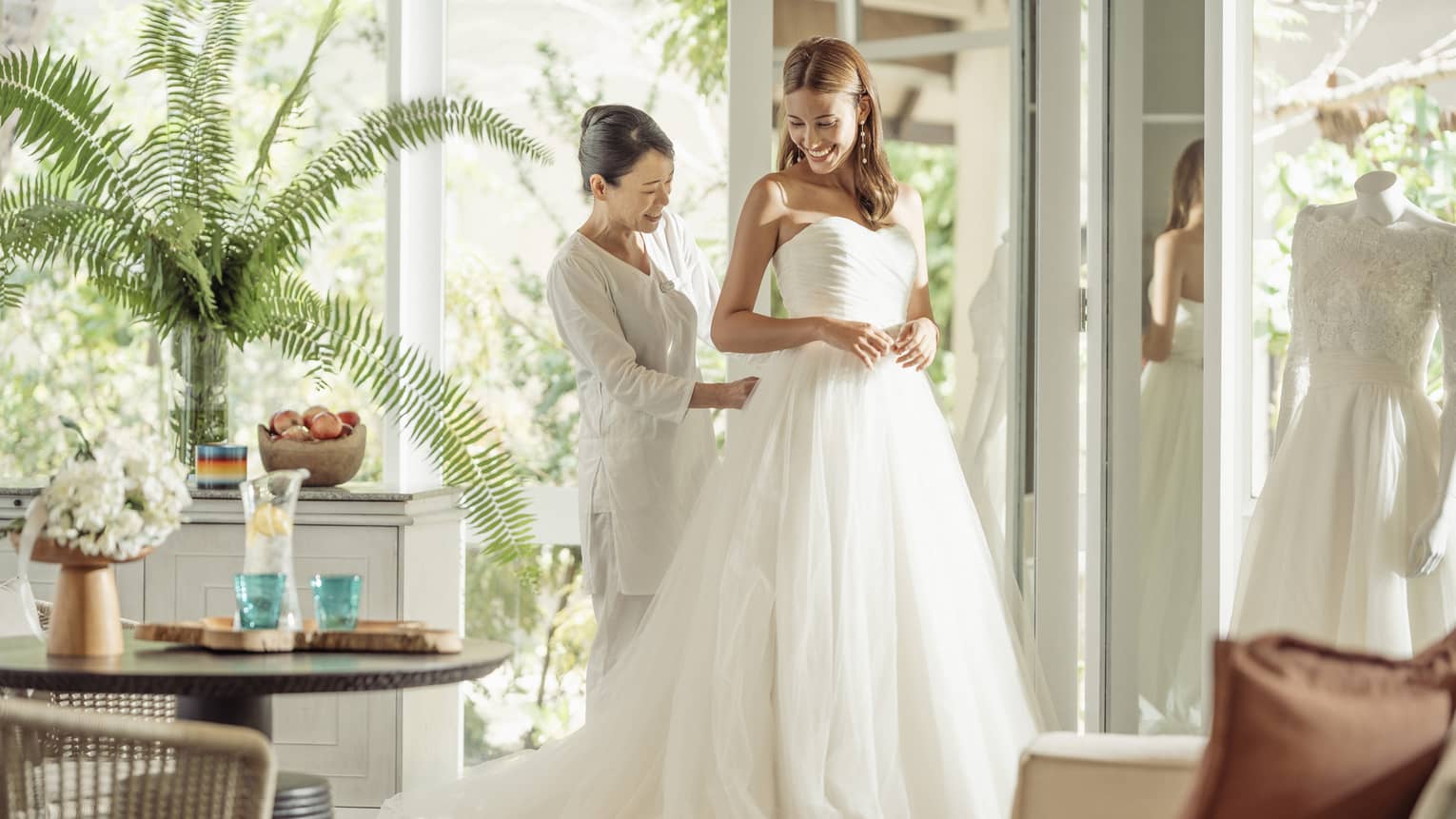 Wedding tailor helps bride in her wedding dress