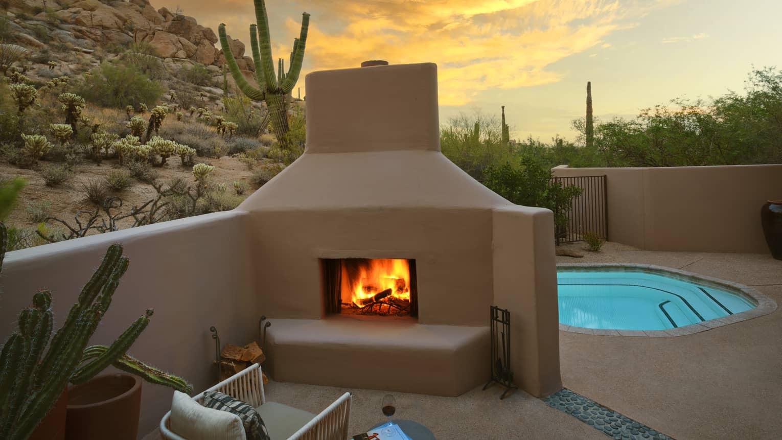 A pool beside a fire pit with a chair, surrounded by desert views
