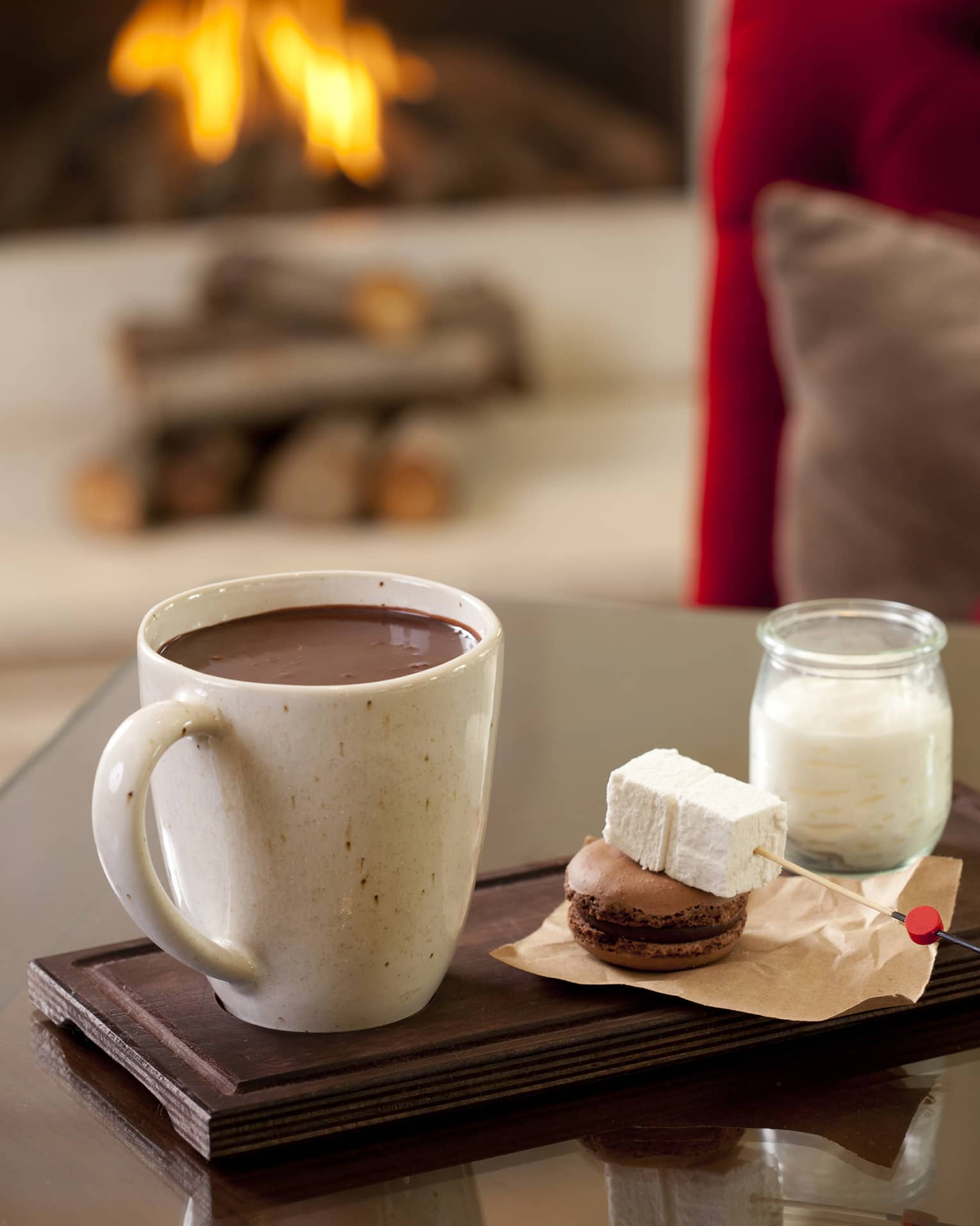 Hot chocolate in large mug beside marshmallow skewer, macaron