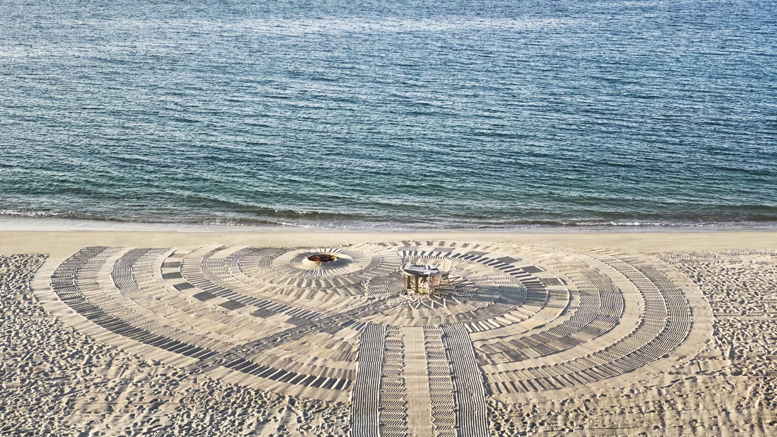 A dining table on a beach next to the water.