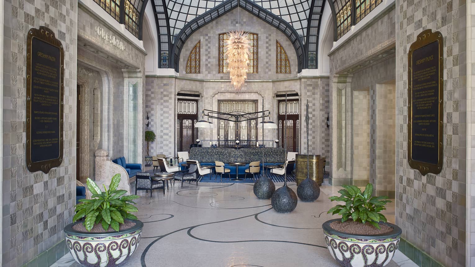 Zrínyi Passage with Zsolnay tiles, white chairs and couch, blue cushions, drapes and high ceiling