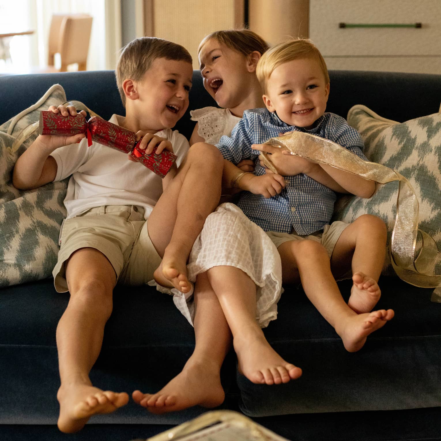 Three young children playing on a sofa.