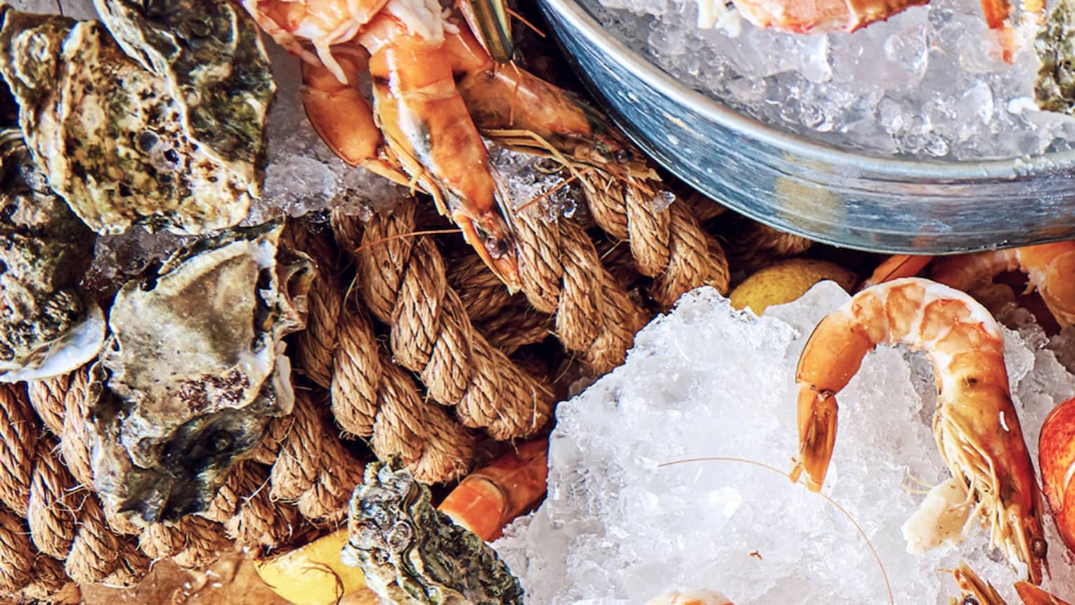 Aerial view seafood platter with whole fish, lobsters, clams and shrimps on bed of ice cubes