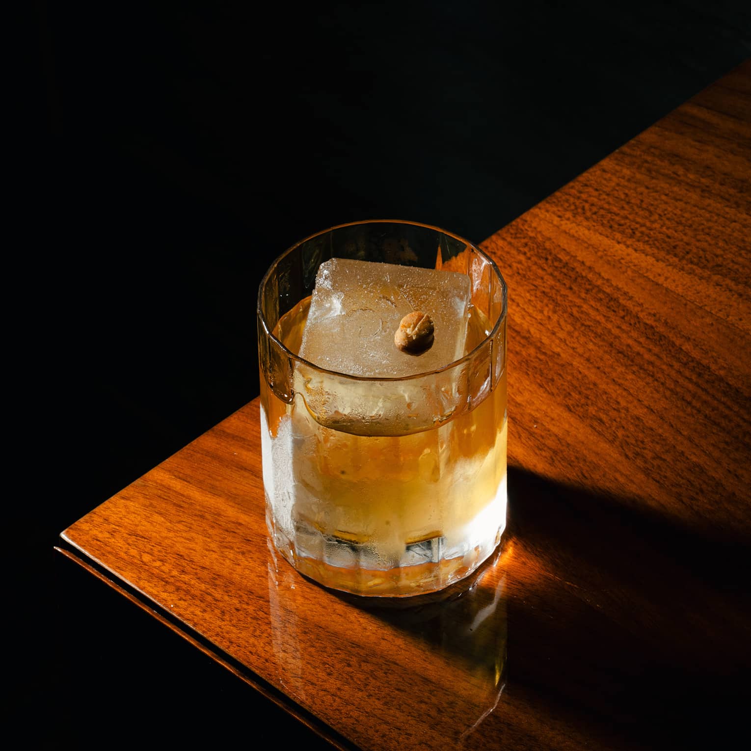 Cocktail in a rocks glass with one large ice cube