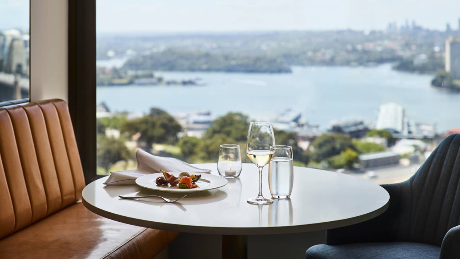 Lounge 32 meal, glass of white wine on round table by window with harbour views