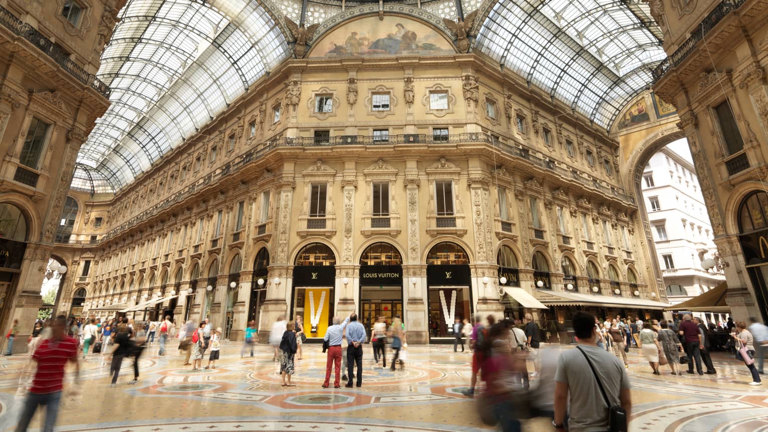 Shoppers gathered in  historic Galleria Vittorio Emanuele building with soaring ceilings, shops