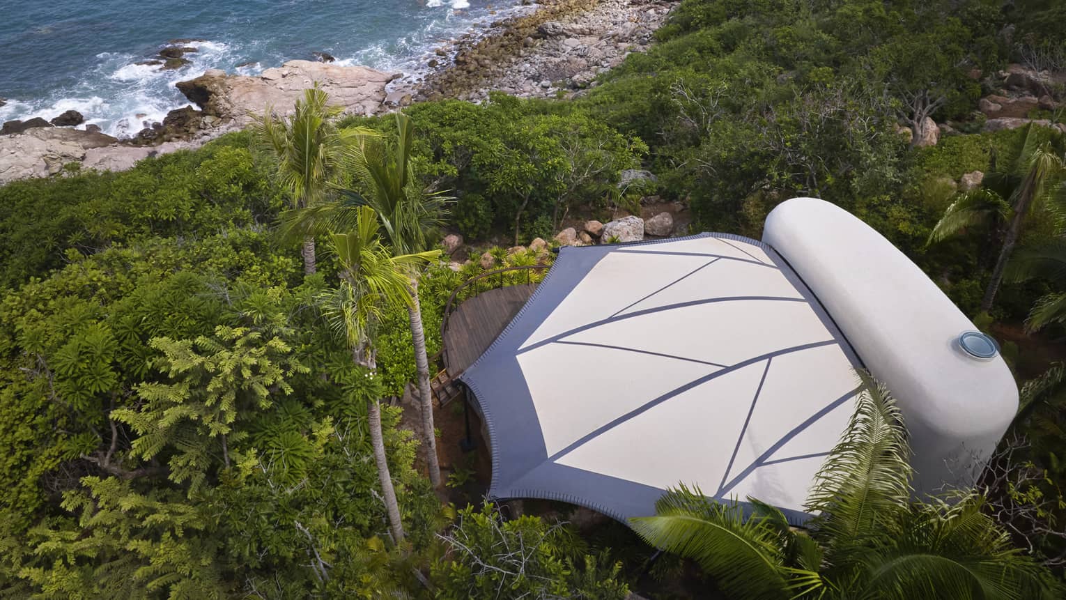 Aerial view of a private luxury tent nestled in the jungle, next to the beach