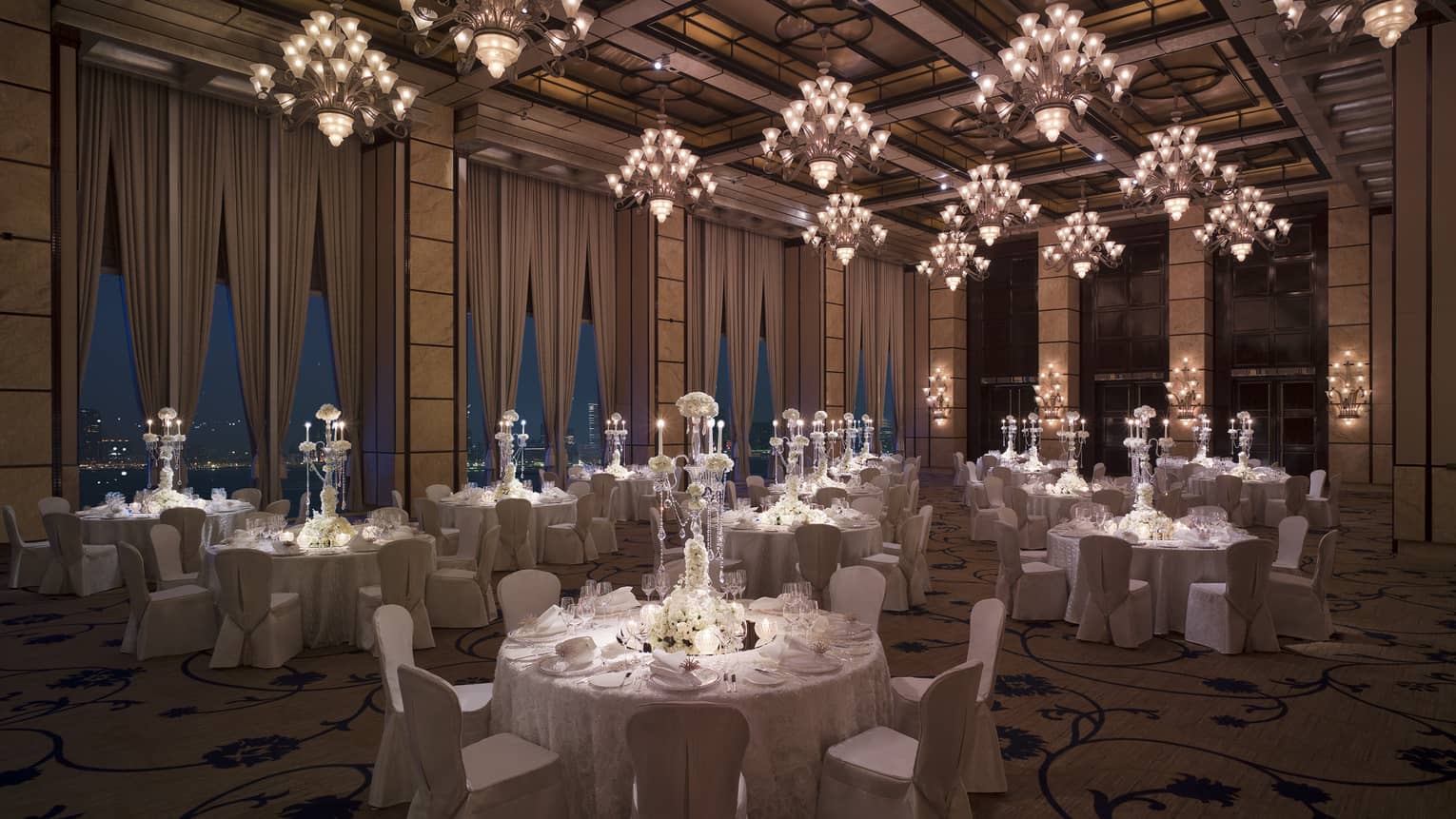 Wedding reception room with round banquet dining tables under small crystal chandeliers
