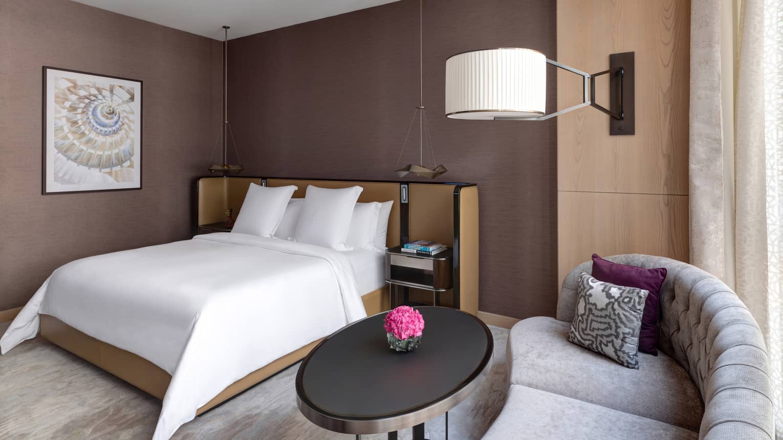 Bedroom with brown walls, king bed and chaise by the window
