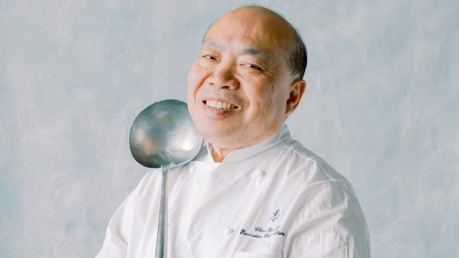 Portrait photo of Chef Chan Yan Tak in uniform and holding large spoon
