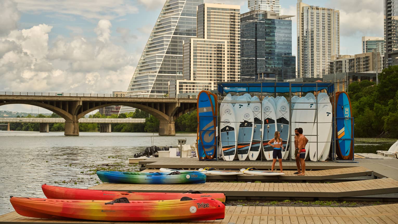 Guests standing on a pier near kayaks and surfboards