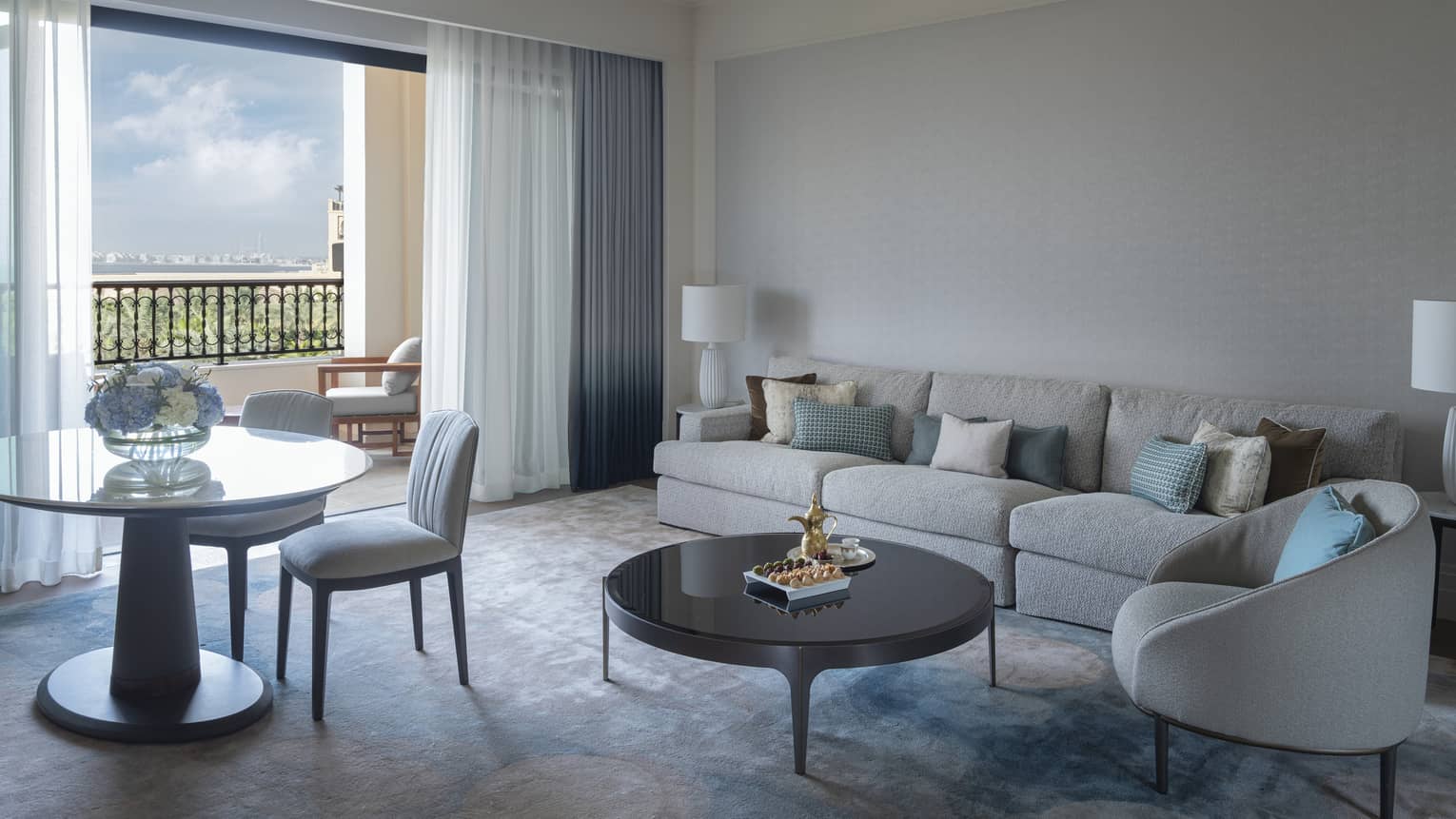 Hotel suite living room with sofa, arm chair, round table and two chairs, and a walk-out terrace