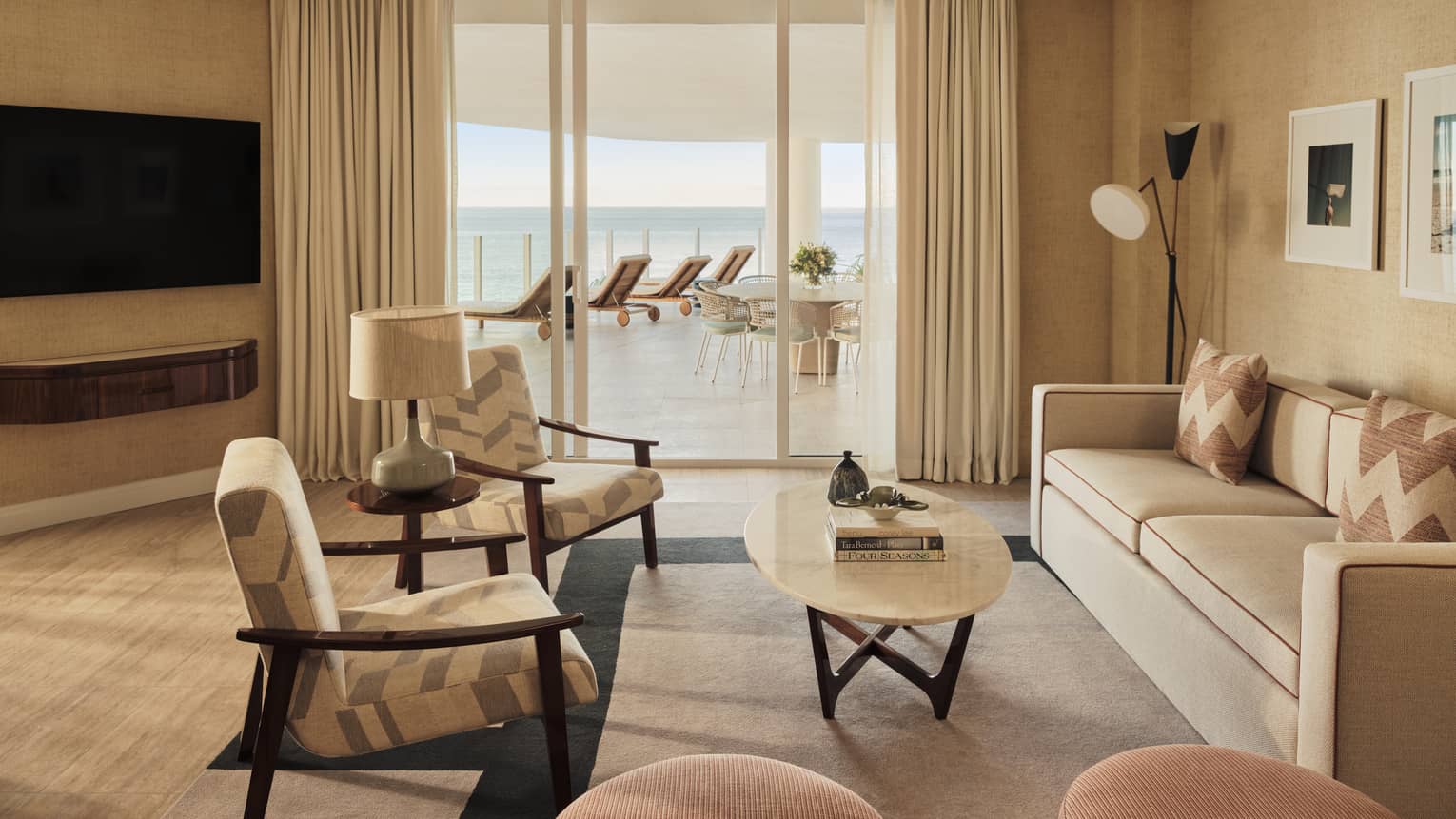 Living room with sofa, two arm chairs, TV, walk-out terrace with ocean view