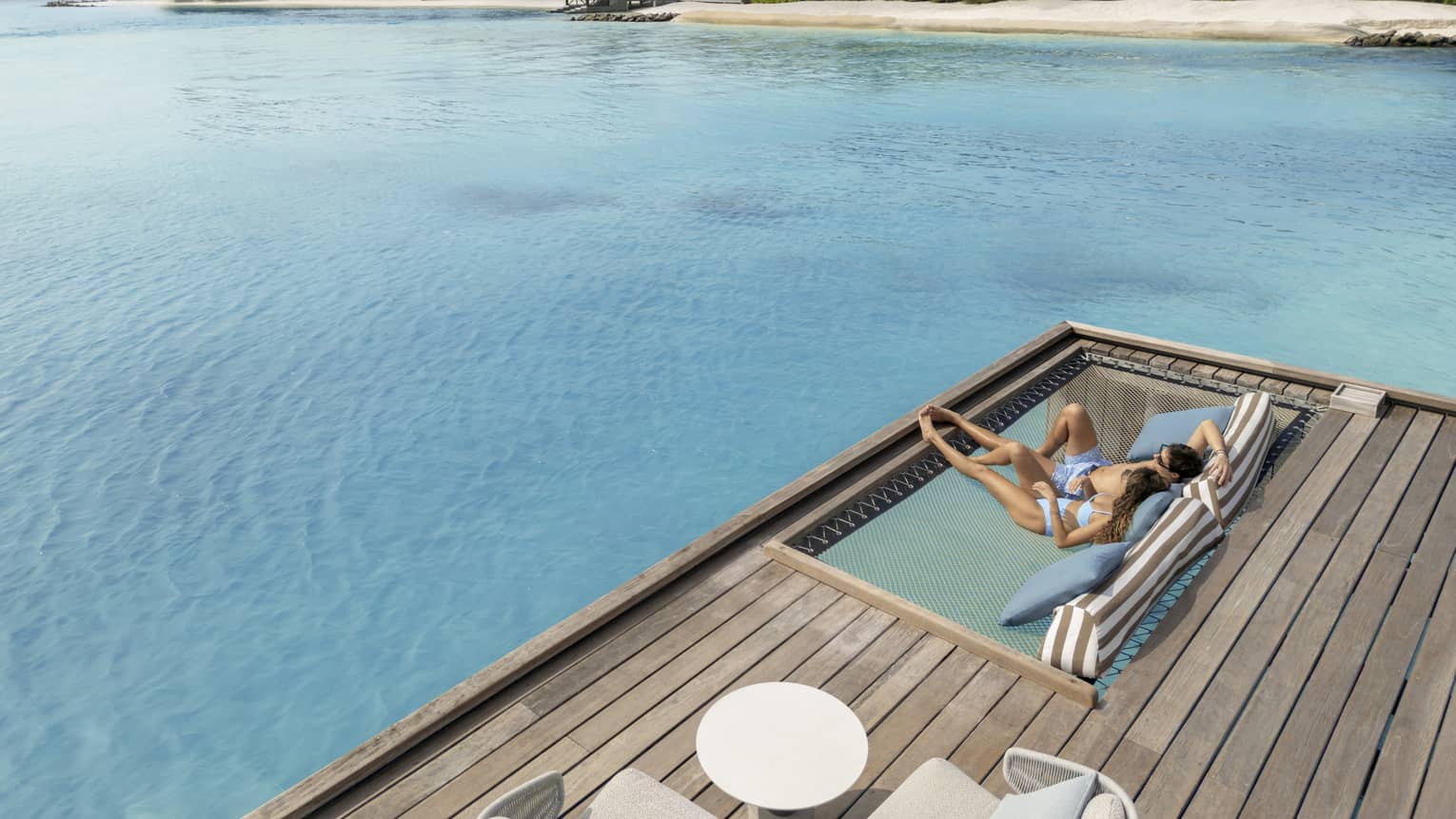 Two people lounge on sundeck as ocean spans out in front of them