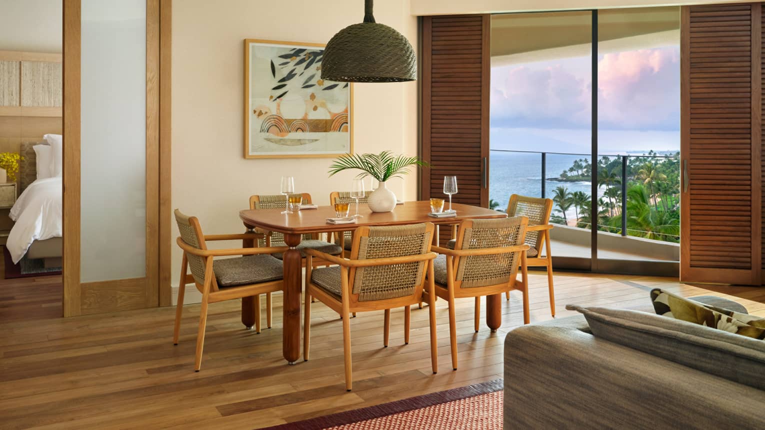 Dining room in an ocean-view resort room, featuring table set for six, and an entryway into a bedroom