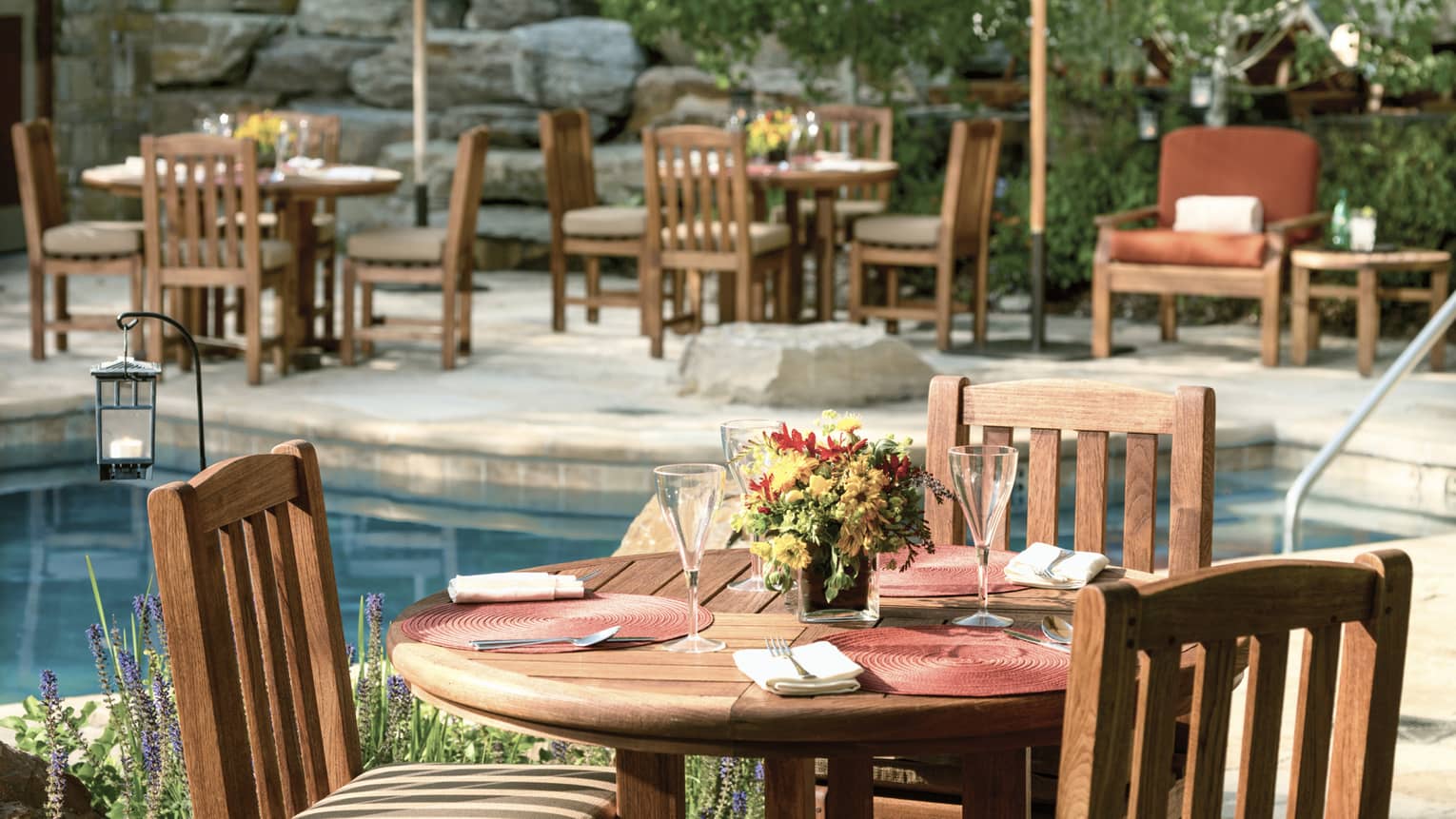 Poolside cafe table-setting with patio umbrellas and fresh-cut flowers.