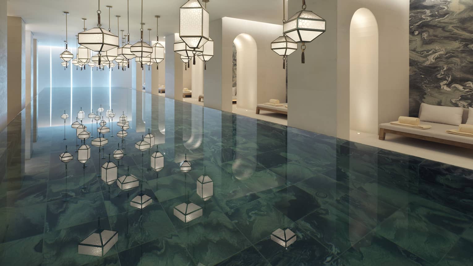 Several modern white lanterns hanging above Indoor Spa Pool, reflected on water 