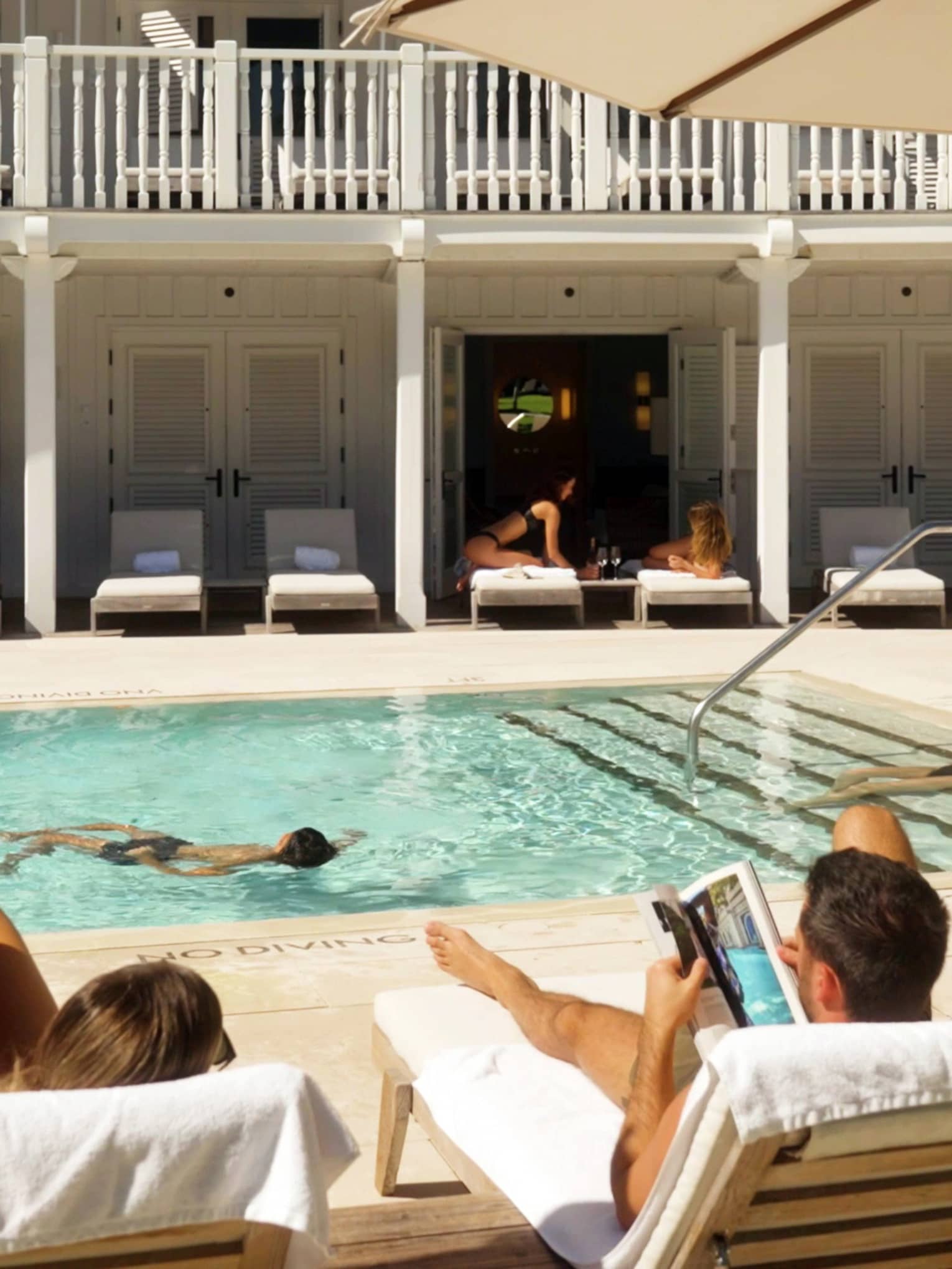 Guests relax on lounge chairs surrounding a hotel pool
