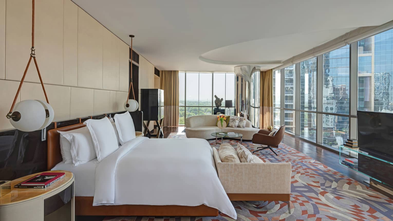 Bedroom with colorful rug, king bed, hanging beside lamps, sitting area