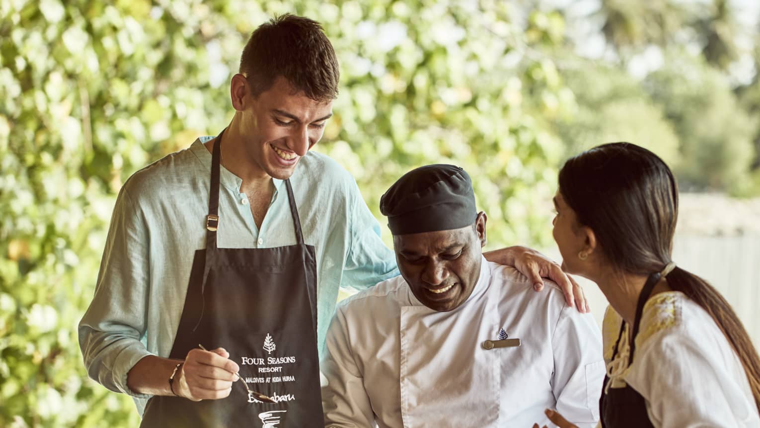 Chef teaches two guests how to make traditional Indian dish in outdoor kitchen
