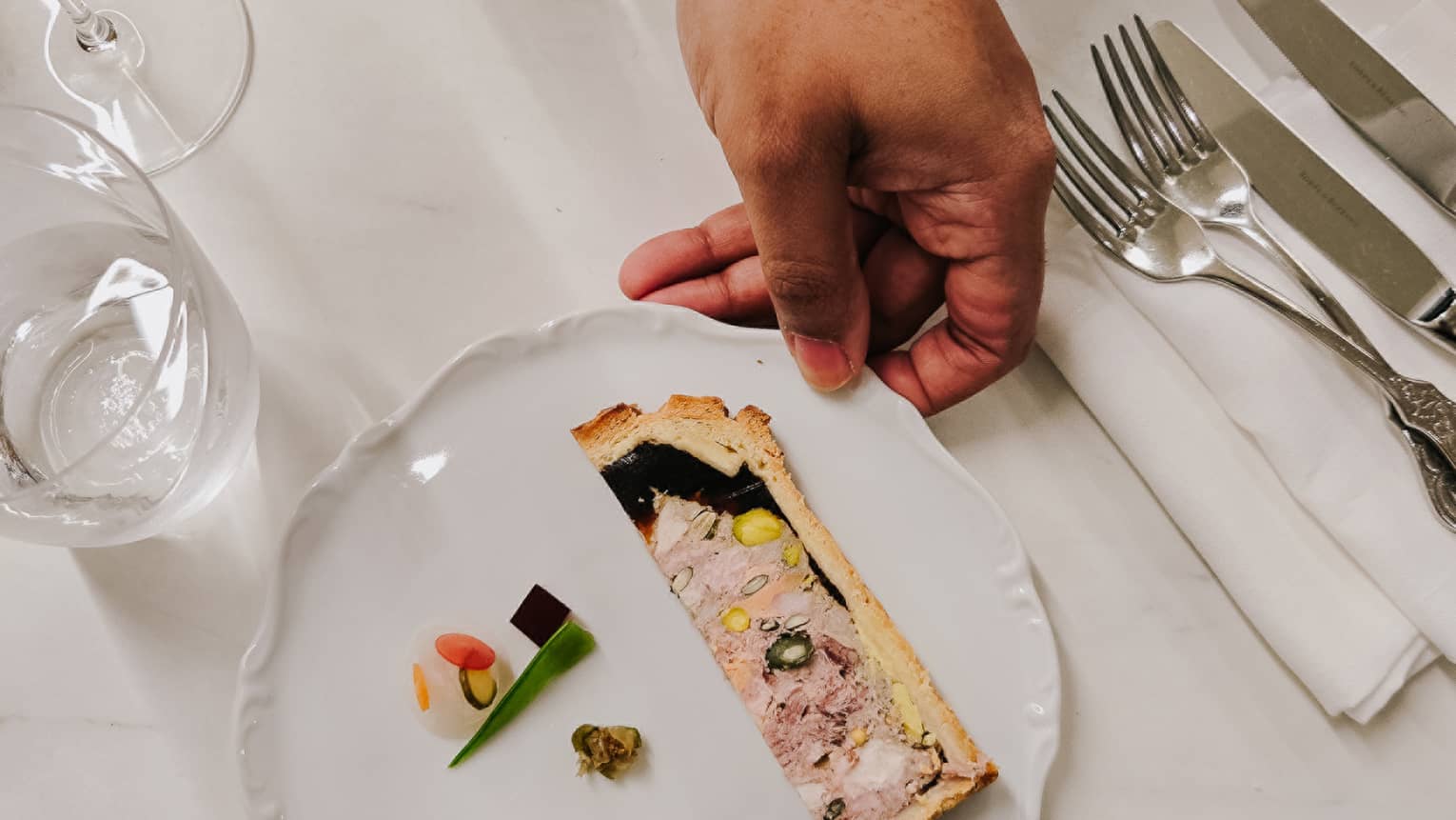 A culinary dish with silverware and wine glasses on the side