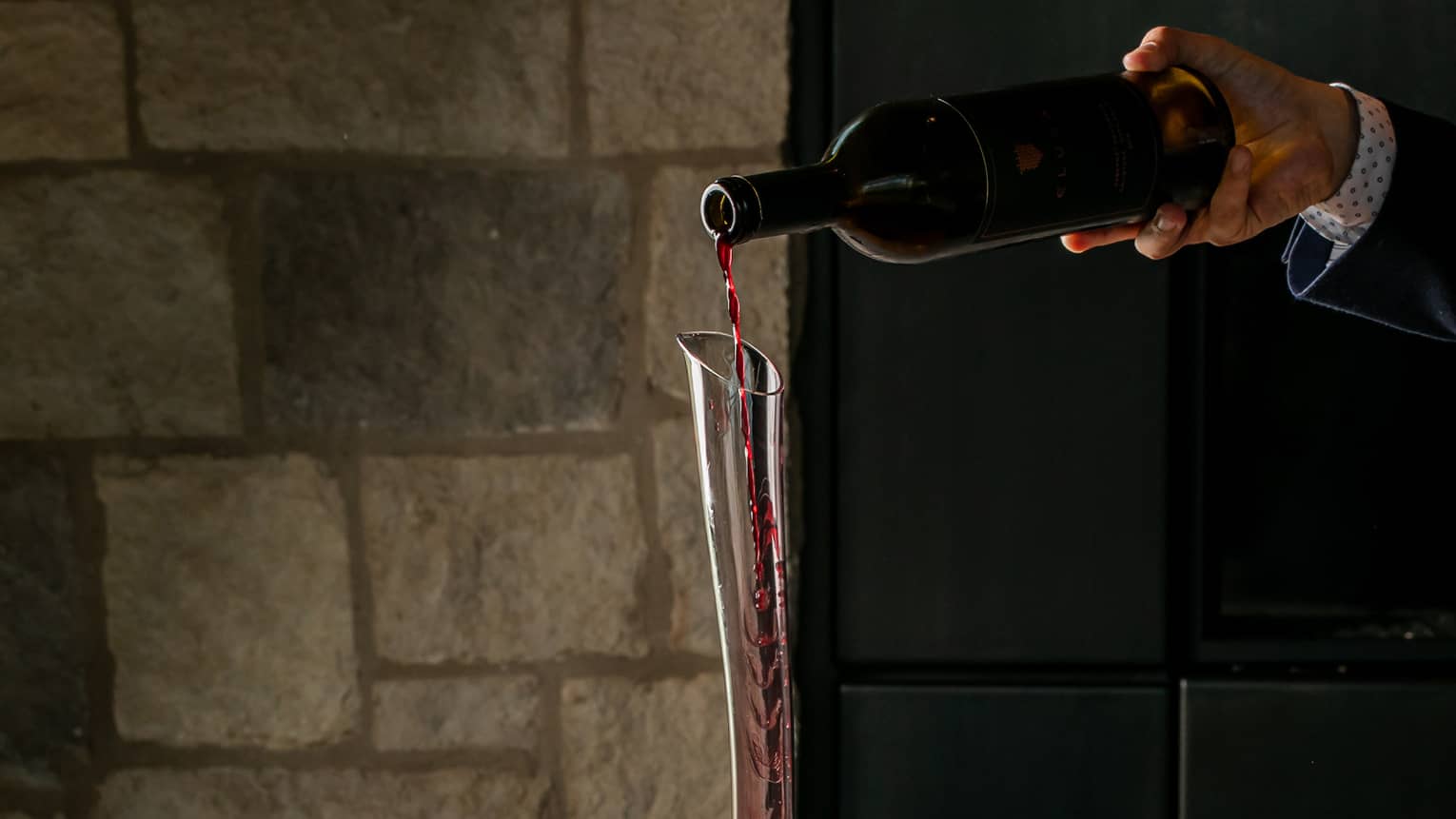 Wine being poured from bottle into wine decanter.