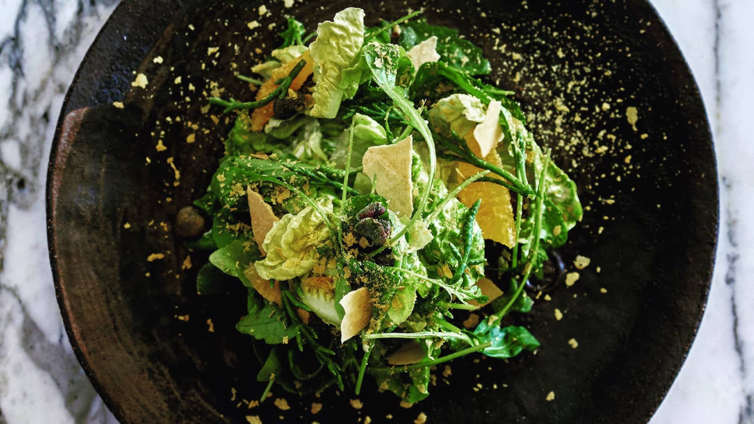 Food detail of contemporary salad on black round plate
