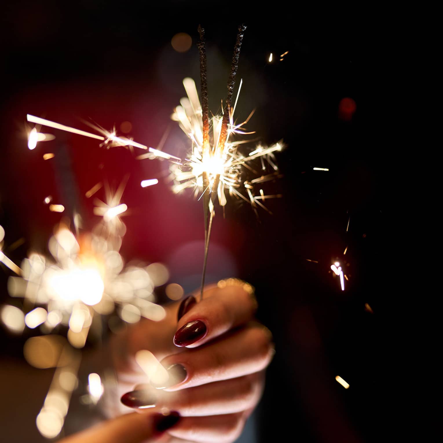 Hands holding a lit sparkler.