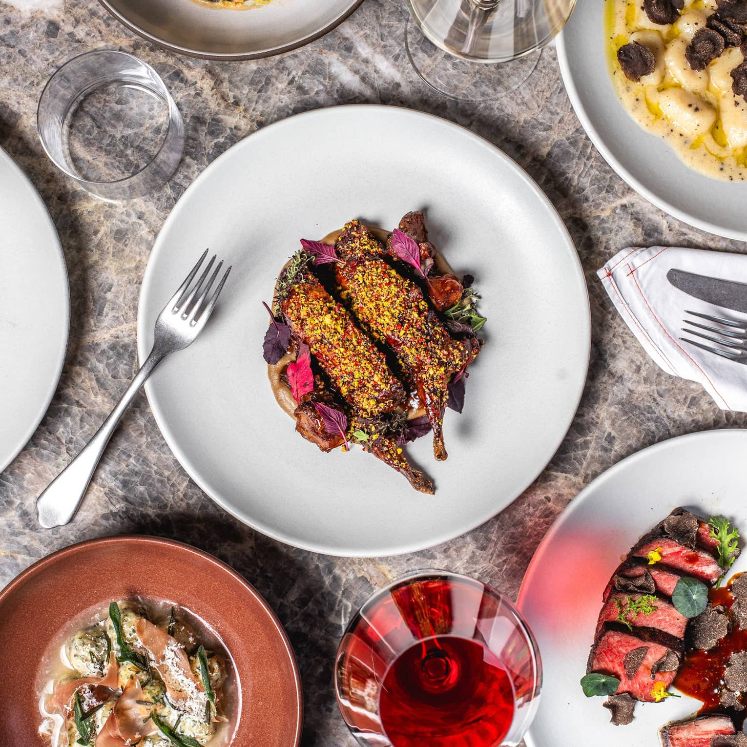 Plates of food on a table with wine glasses and silverware