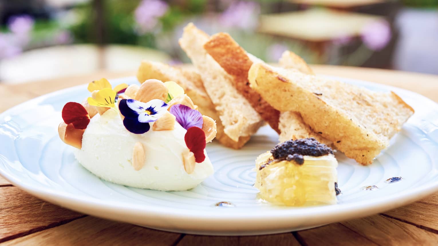 Whipped ricotta on plate with edible flower garnish, honeycomb, toast