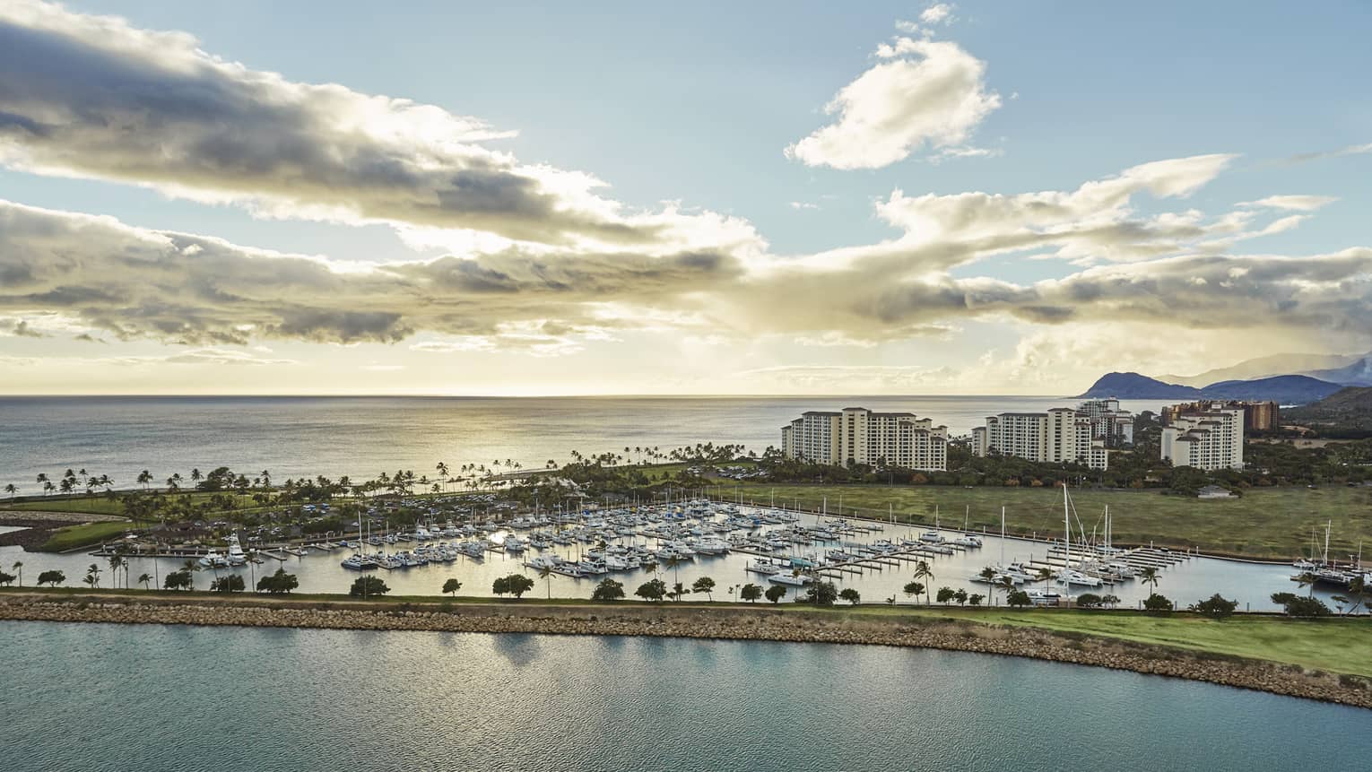 Aerial view of harbour lined with yachts, resort buildings at sunset