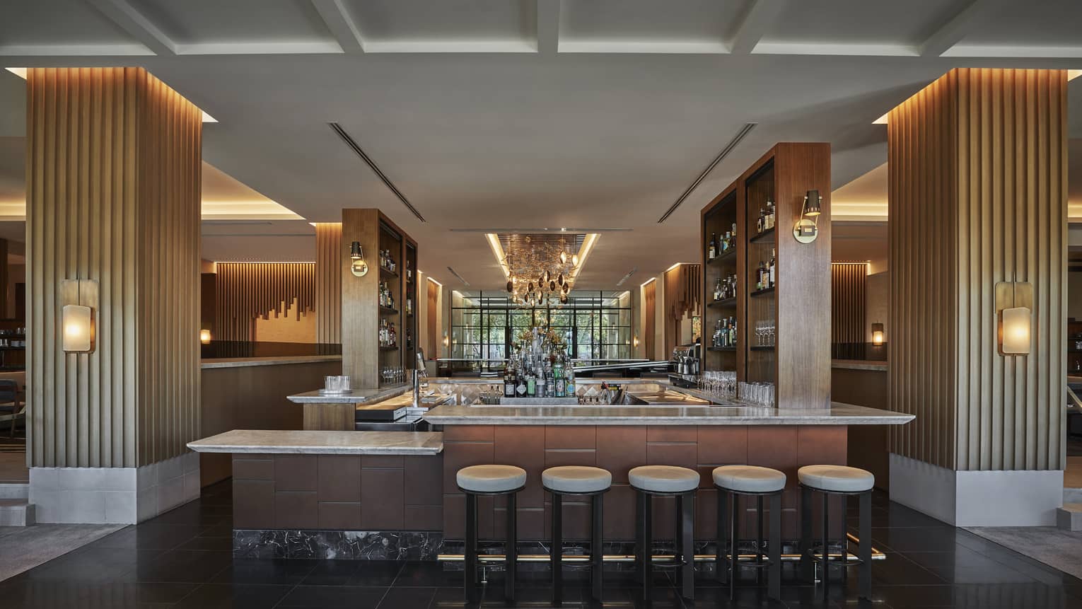 A dimly lit bar area with round stools and stripes columns down the side.