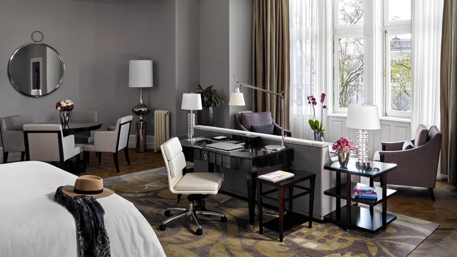 River-View Park Suite bed with hat and scarf, desk, loveseat and armchairs in front of large picture window