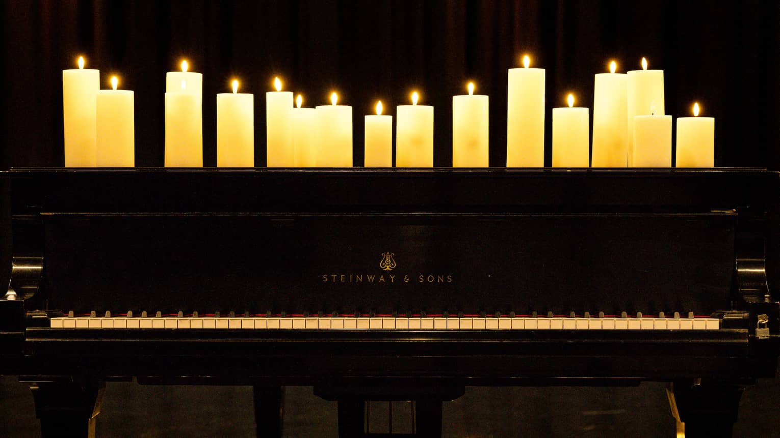 Pillar candles fill the top of a black piano