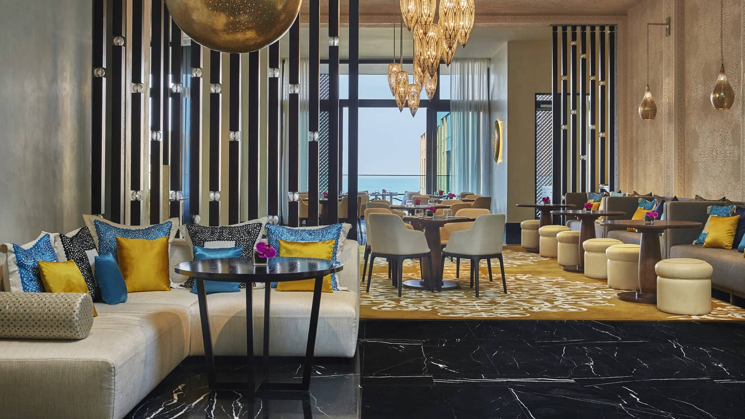 Mint restaurant sofa with bright blue and yellow silk pillows, dining room, large brass lamps and lanterns