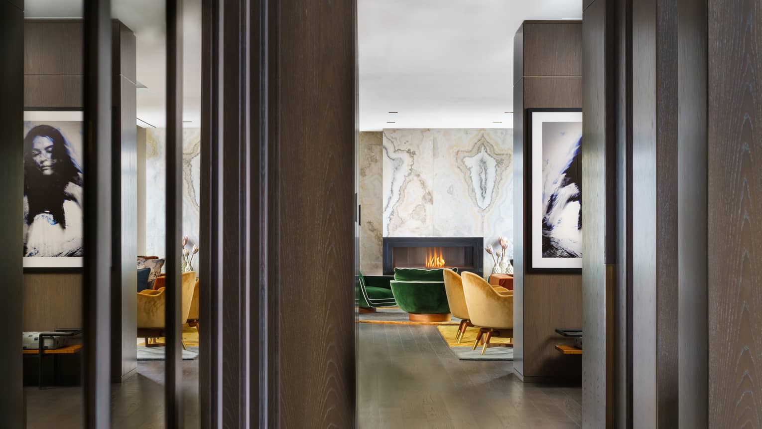 Entryway to suite, dark wood floors, mustard- and emerald green-coloured arm chairs by fireplace