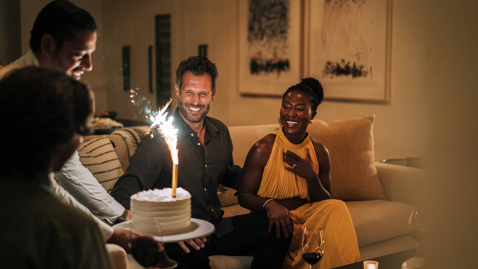 Staff member presenting guests with a lit birthday cake in a residence living room