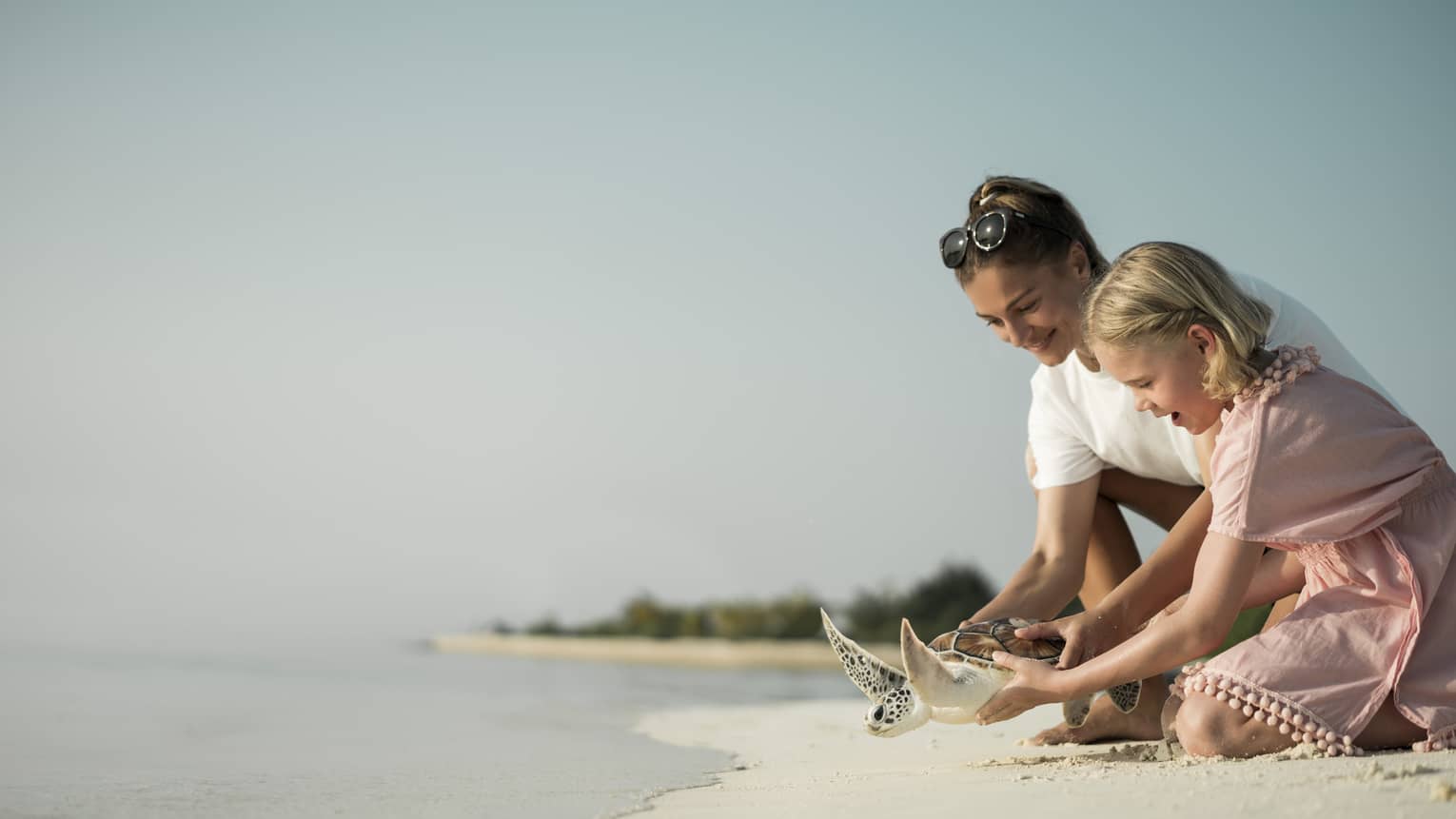 Marine Discovery Centre. Woman and daughter help release a sea turtle back in ocean