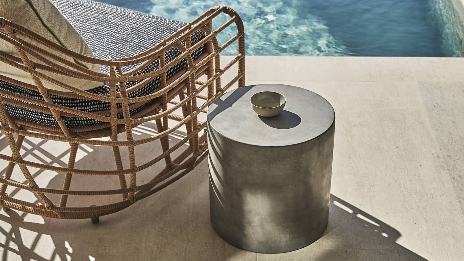 A chair and metal table next to a small outdoor pool.