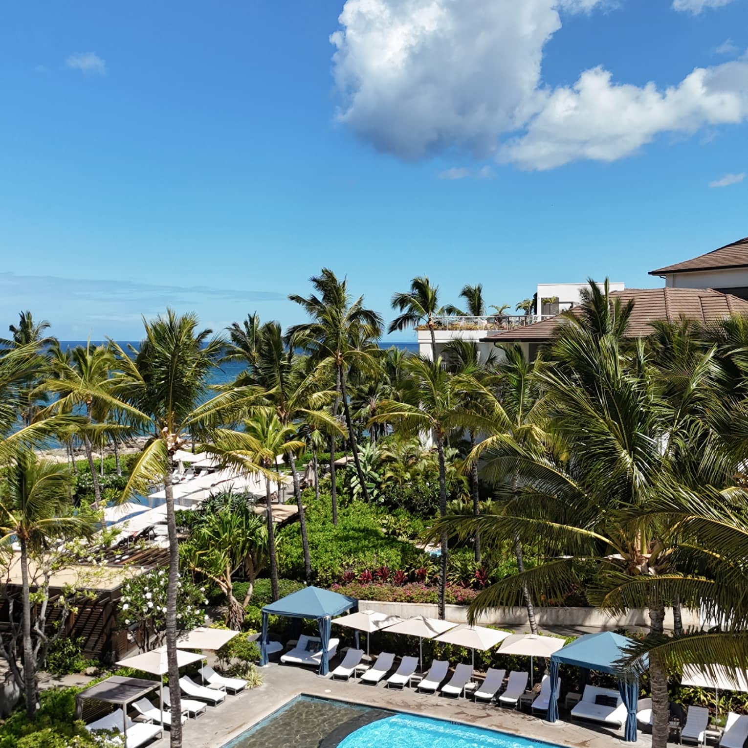 Family pool at luxury Hawaiian resort, lined with beach chairs and cabanas
