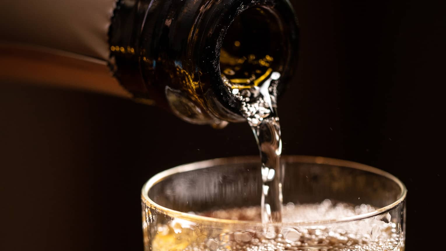 A bottle of wine being poured into a glass.